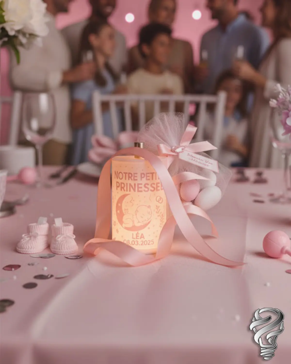 Mini-lampe ILM3D Baby “Notre petite princesse” sur table de fête rose, décorée de rubans et dragées, centre de table pour naissance ou baptême.